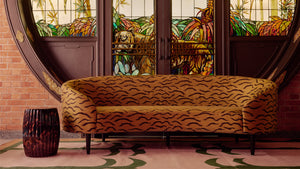 Set against the beautiful stained glass tiger doors of the Har Paw mansion, our re-upholstered curved sofa in Jim Thompson's Seregeti Topaz fabric site atop of our green and pink palm dhurrie rug.